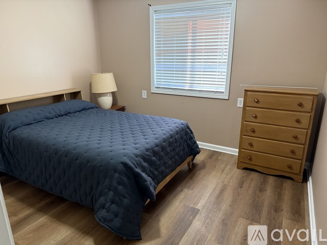 A bedroom with a bed, dresser, and window.
