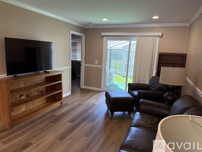 A living room with a flat screen TV and a brown leather couch.