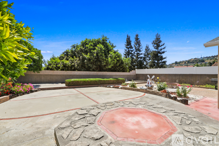 A backyard with a red circular pool and a stone border.