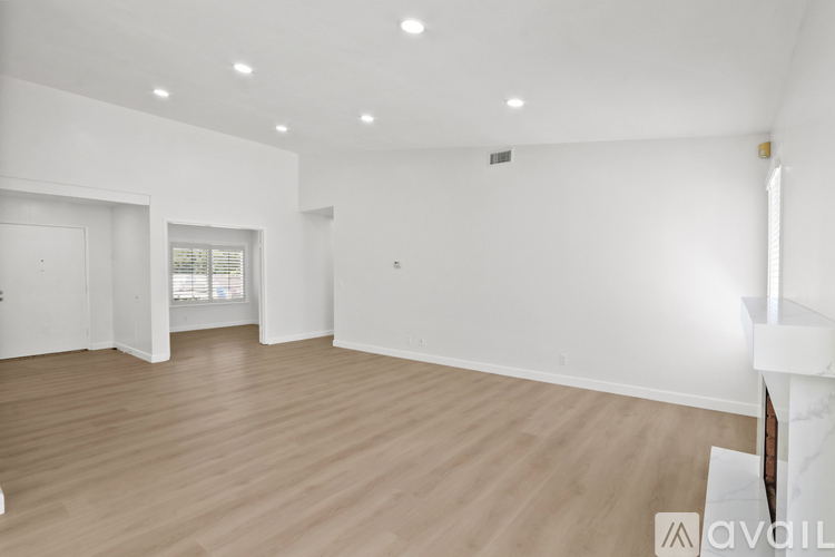 A spacious room with wooden flooring and white walls.