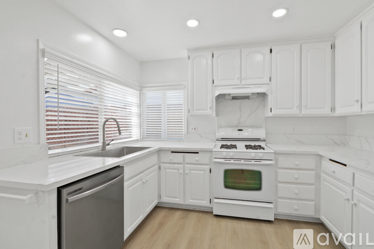 A kitchen with white cabinets and appliances.