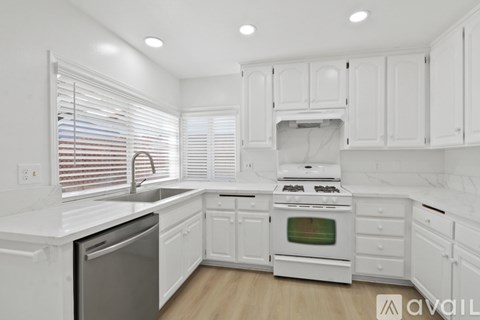 A kitchen with white cabinets and appliances.