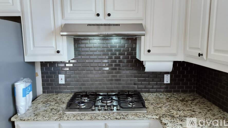 A kitchen with a granite countertop and a stove top.