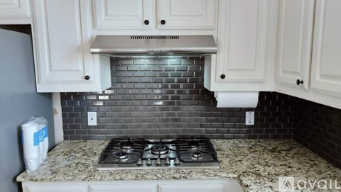 A kitchen with a granite countertop and a stove top.