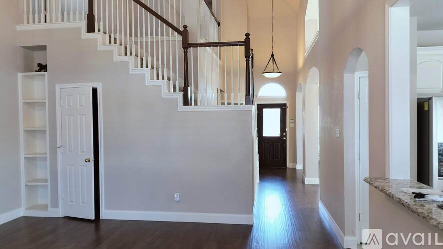 A spacious room with a staircase and a door leading to another room.