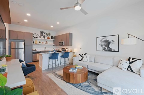 A modern living room with a white sofa and a kitchen area in the background.