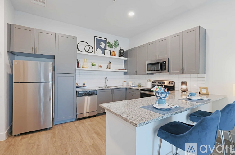 A kitchen with a refrigerator, microwave, and a counter with two chairs.