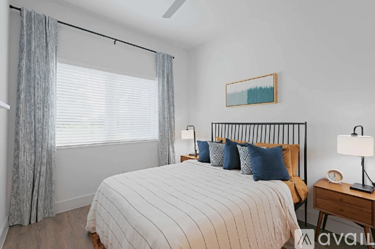 A bedroom with a bed, nightstand, and window with curtains.