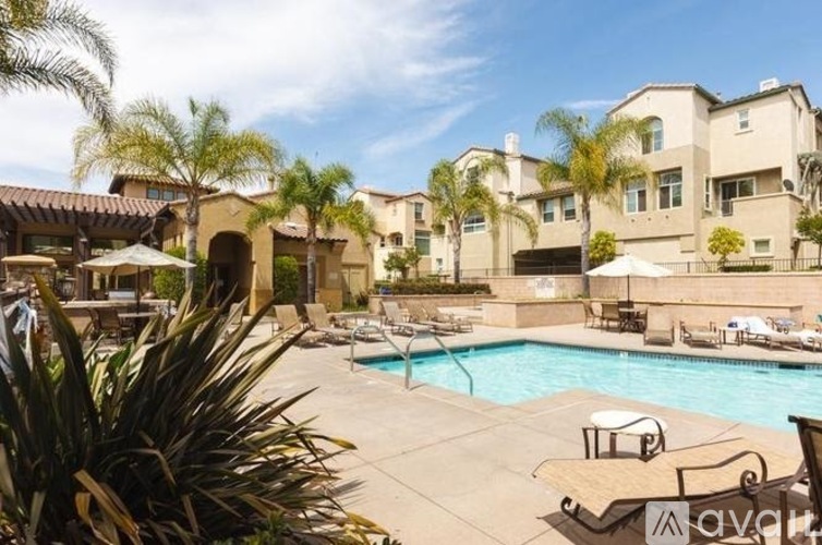 A pool surrounded by chairs and umbrellas with a building in the background.