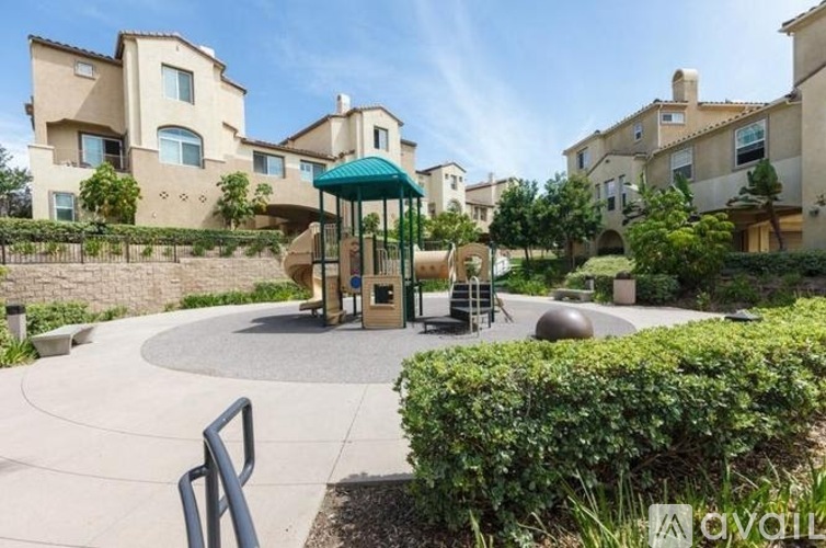 A playground area with a slide and a green canopy is surrounded by residential buildings.