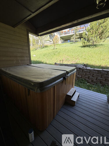 A hot tub on a deck with a bottle next to it.