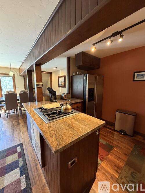 A kitchen with wooden cabinets and a checkered rug on the floor.