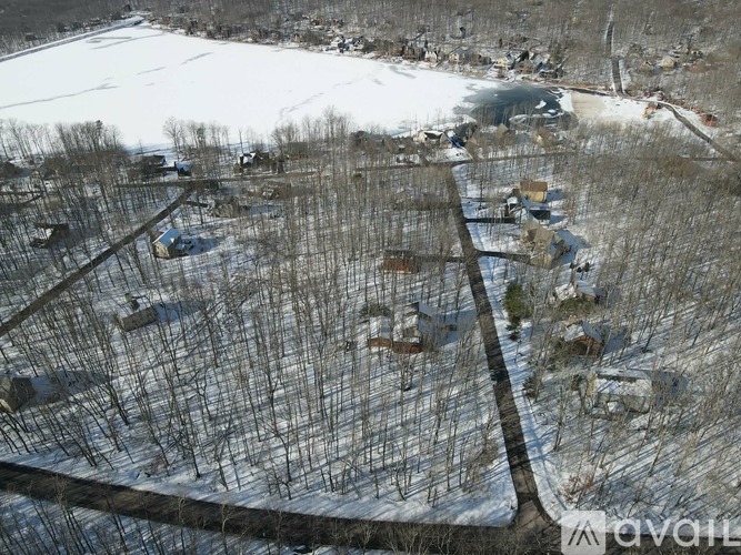 A snowy field with a fence and some buildings.