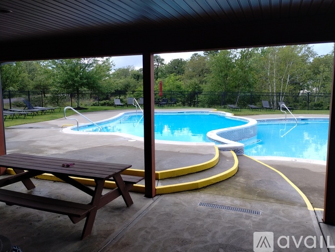 A wooden picnic table is in front of a swimming pool.
