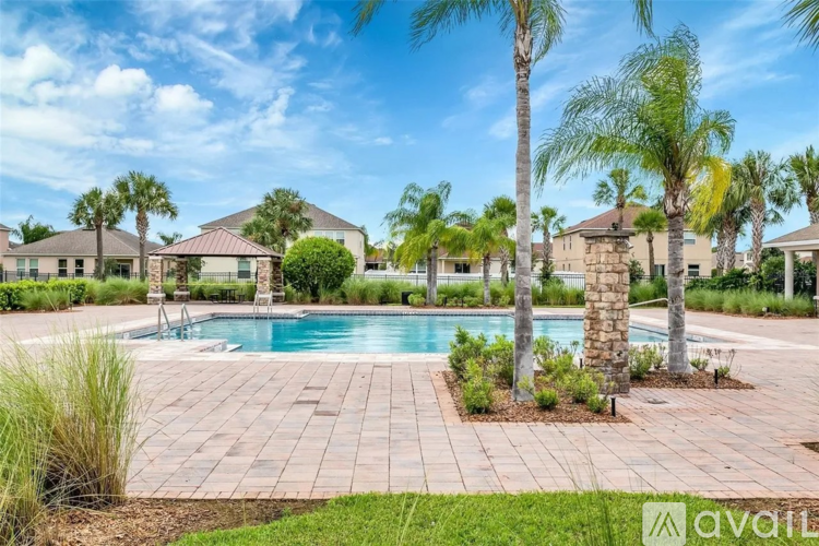 A pool surrounded by palm trees and a brick patio.