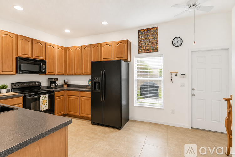 A kitchen with wooden cabinets and a black refrigerator.