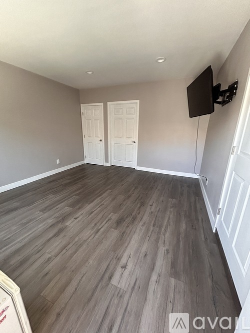 A room with wooden flooring and a flat screen TV mounted on the wall.
