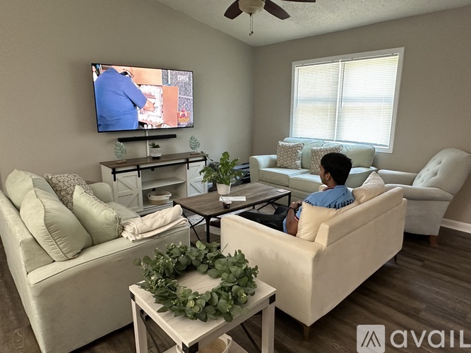 A woman is sitting on a couch watching television in a living room.