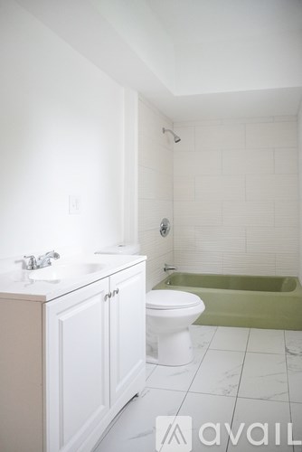 A white bathroom with a green tub.