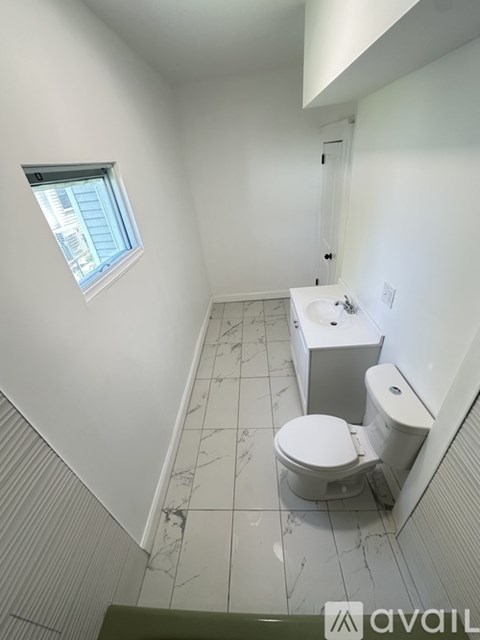 A bathroom with a toilet, sink, and window.