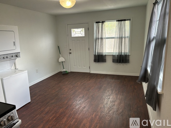 A room with a wood floor and a window with curtains.