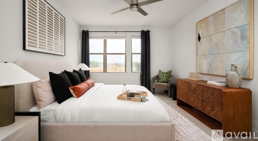 A bedroom with a large bed, a ceiling fan, and a wooden dresser.
