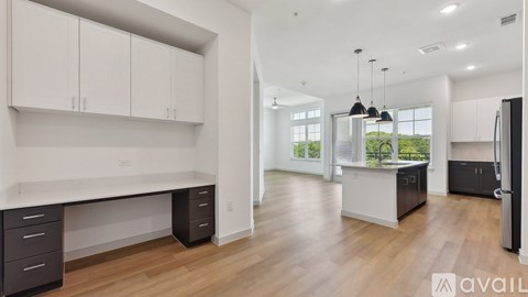 A modern kitchen with white cabinets and a wooden floor.