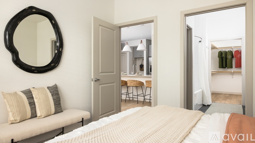 A bedroom with a round mirror and a bed with a white blanket.