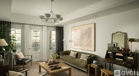 A living room with a green sofa, a wooden coffee table, and a large painting on the wall.