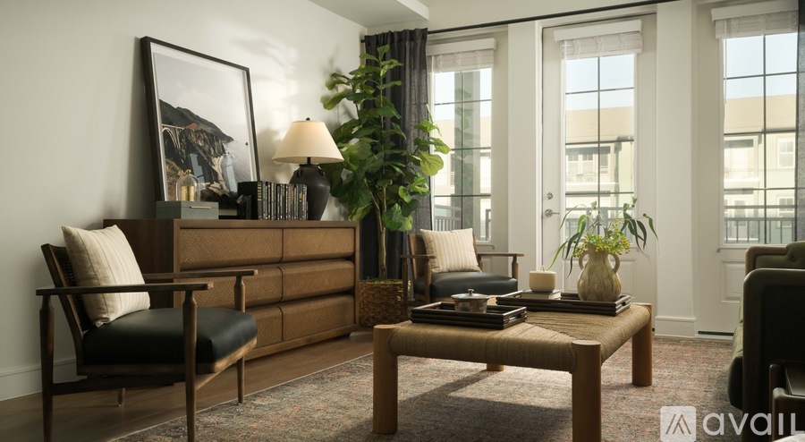 A living room with a brown sofa, a black chair, a wooden coffee table, and a large window.