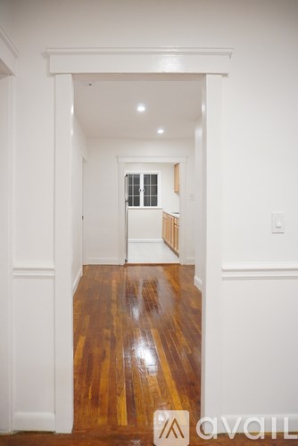 A hallway with wood floors and white walls.