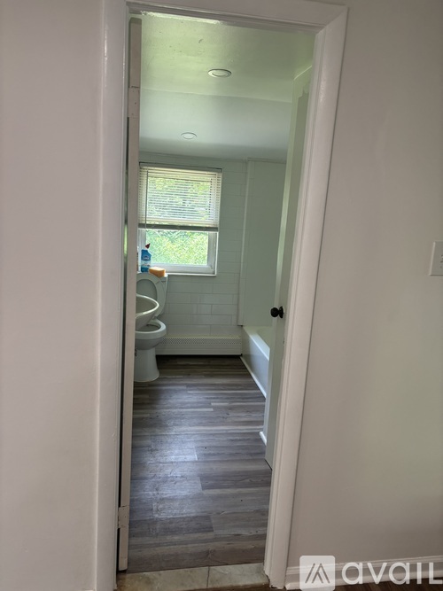 A bathroom with a toilet, sink, and window.