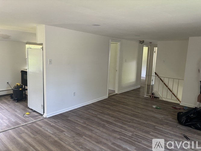 A room with wooden flooring and white walls is being prepared for a new tenant.