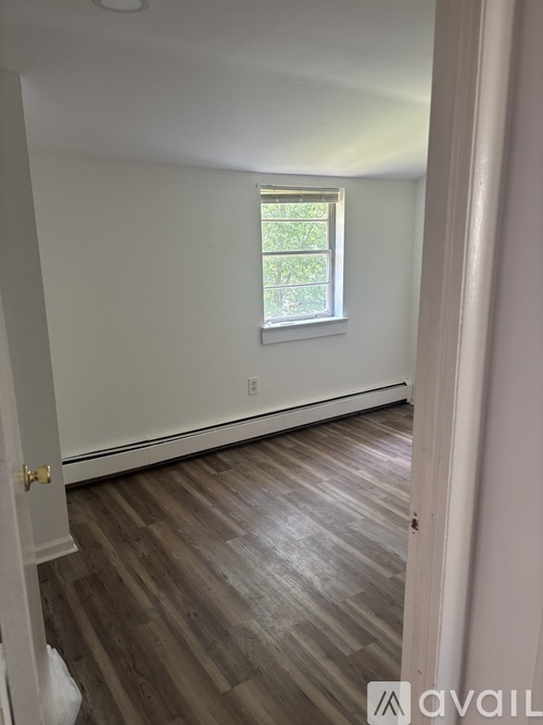 A room with a window and wooden flooring.