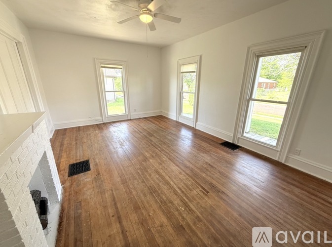A room with wooden flooring and a fireplace on the left side.