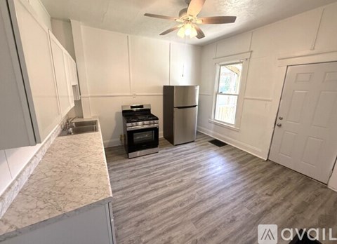 A kitchen with a fan, a fridge, and a stove top oven.