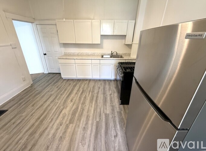 A kitchen with a stainless steel fridge and wooden flooring.