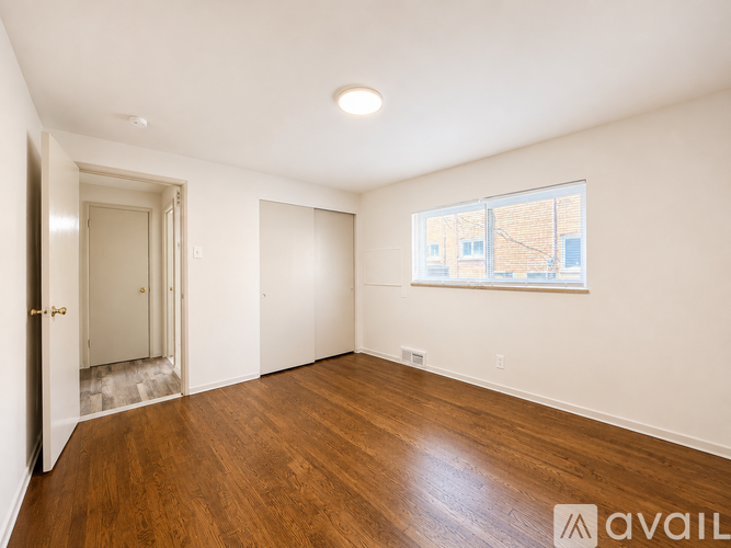 A room with wooden floors and a window showing a view of a building outside.