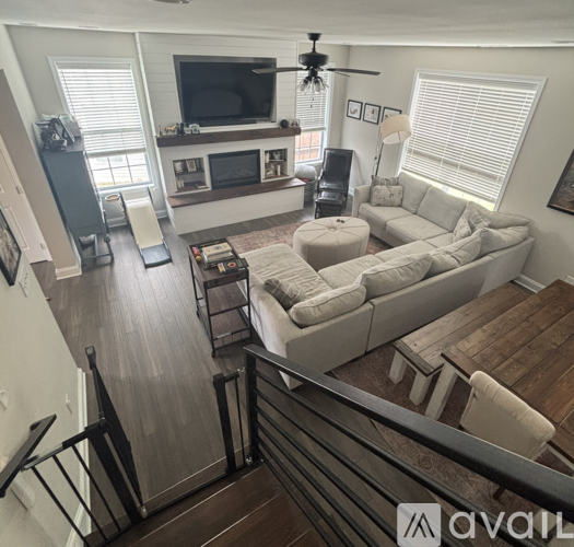 A living room with a couch, a television, and a ceiling fan.