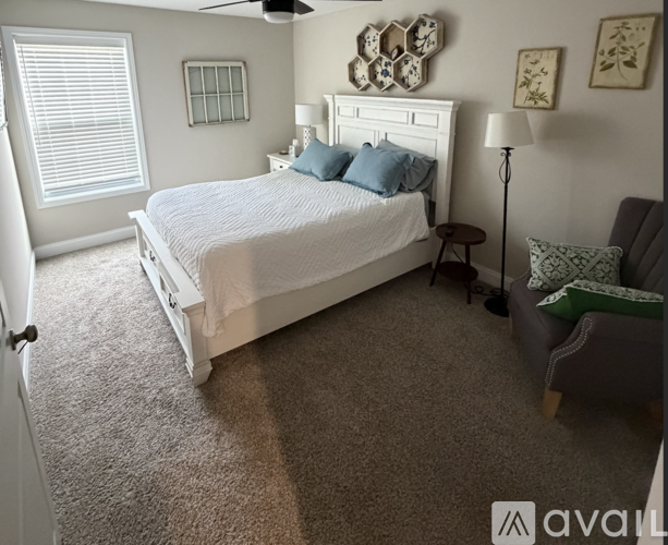 A bedroom with a white bed and a ceiling fan.