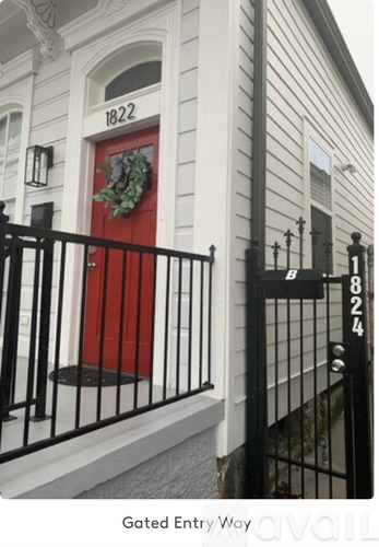 A red door with a wreath on it and a black gate.