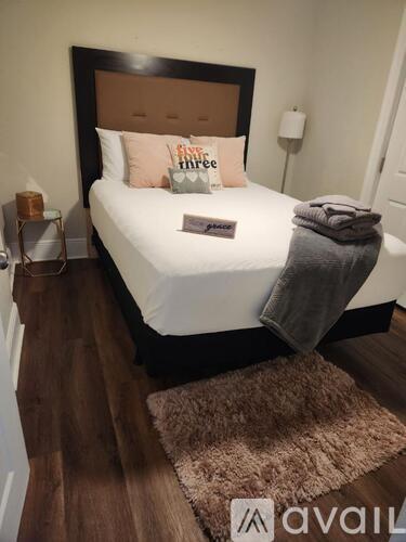 A bedroom with a white bed and a brown headboard.