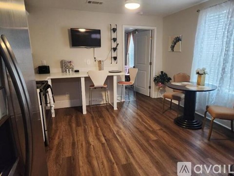 A kitchen with a refrigerator on the left and a dining table with chairs in the middle.