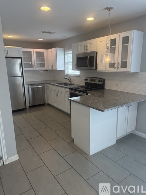 A kitchen with white cabinets and a granite countertop.