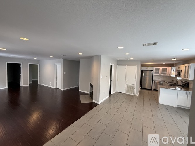 A spacious living area with a kitchen in the background.