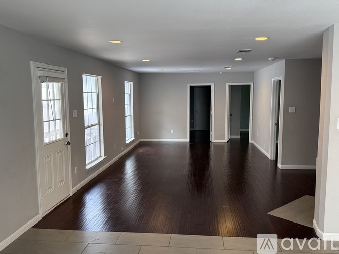 A spacious room with wooden floors and white walls.