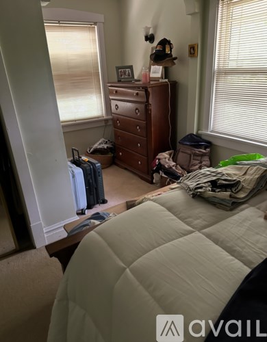 A bedroom with a bed, dresser, and window with blinds.