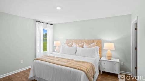 A well-lit bedroom with a large bed and a nightstand with a lamp.