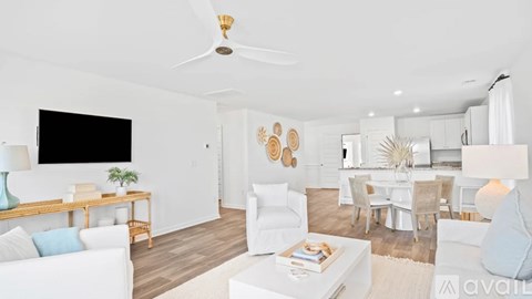A living room with a white couch, a wooden table, a television, and a ceiling fan.