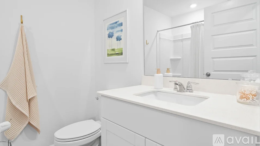 A bathroom with a toilet, sink, and a painting on the wall.
